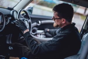 Mechanic using a diagnostic tool on a car's dashboard.