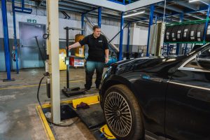 Mechanic at Mr Tyre Rochdale doing headlight checks on a black car.